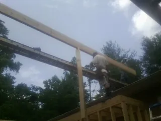 Carpenter setting a ridge beam over a new addition frame — Ice Dam Removal by Roofing Brothers in Rowesville