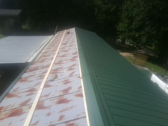 Old rusted panels beside newly installed green metal roofing — Wind Damage Roof Repair by Roofing Brothers in Rowesville
