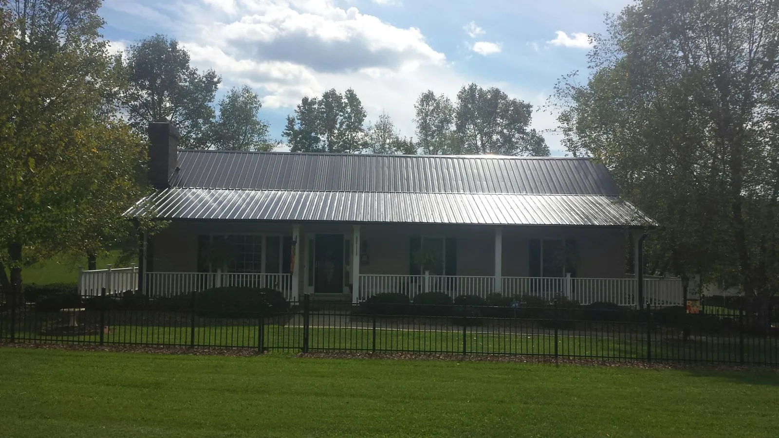 Gray metal roof on a brick ranch with a full width front porch — Gutter Guard Installation work by our crew in Rowesville