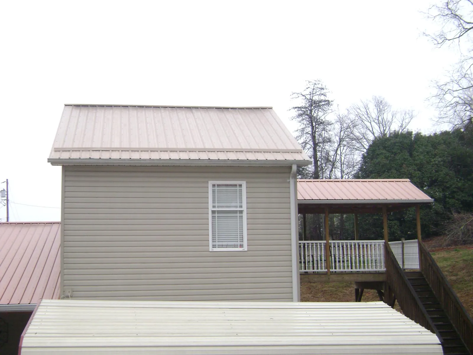 Tan metal roofs on a two story addition and attached porch, from a Roof Replacement job in Rowesville