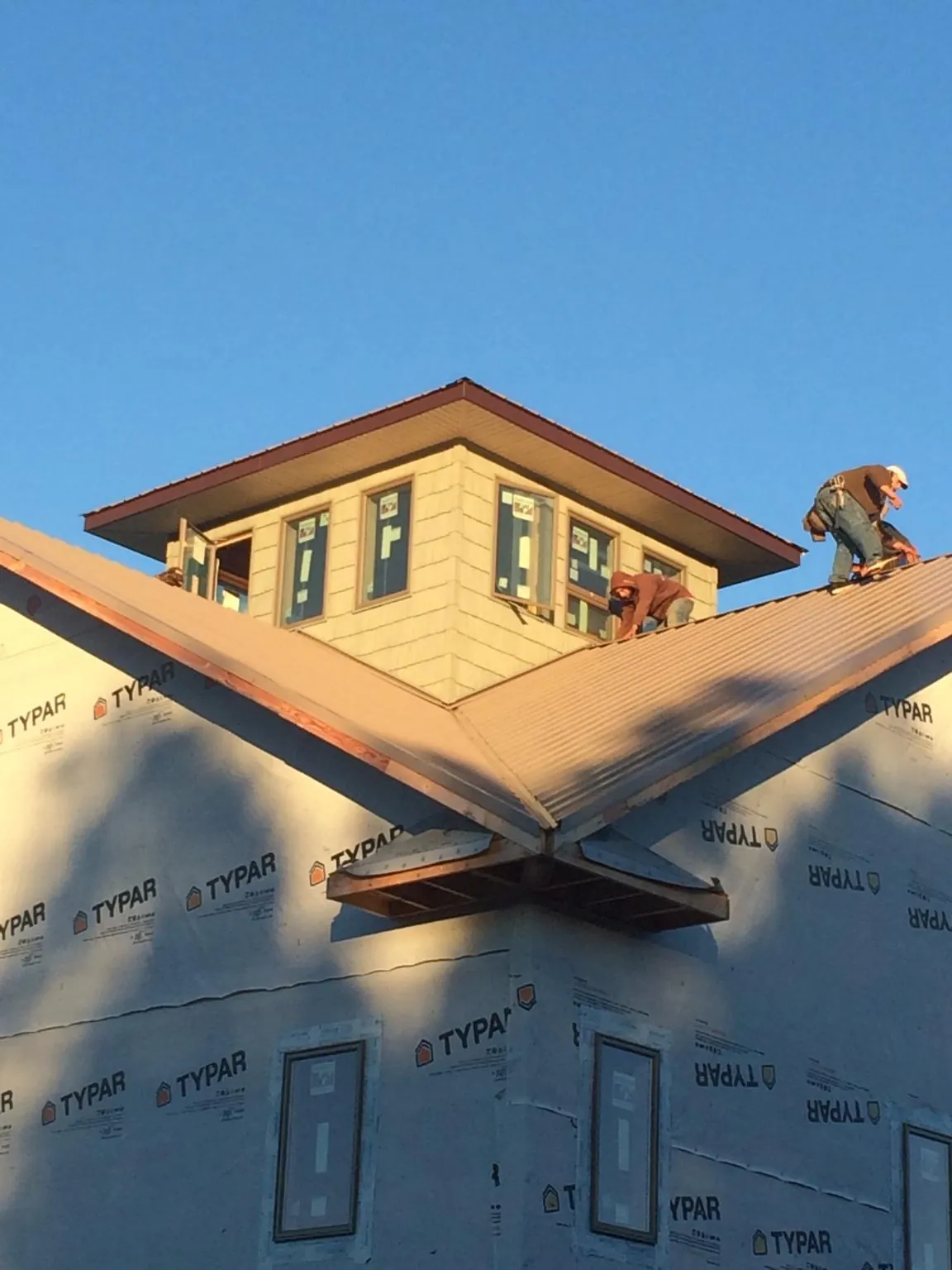 Roofers working around a rooftop cupola on a new metal roof at sunset — Roof Waterproofing in Rowesville by Roofing Brothers